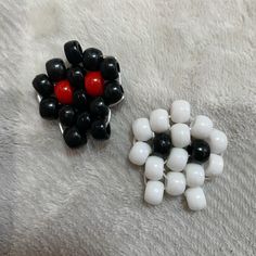 two pieces of black and white beads sitting on top of a fur covered floor next to each other