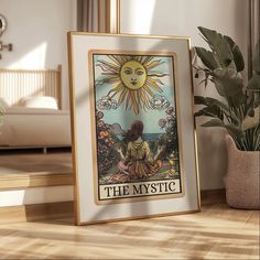 a framed tarot card sitting on top of a wooden floor next to a potted plant