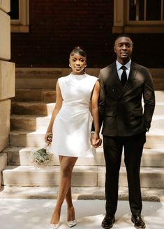 a man and woman standing next to each other in front of some steps holding hands