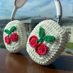 two crocheted strawberry purses sitting on top of a wooden table next to a window