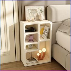 a white shelf with some books and other items on it in front of a bed