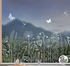 a window with flowers and butterflies drawn on it, in front of a mountain range