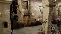 an old stone house with potted plants on the wall and tables in the hallway