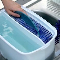 a person holding a blue brush in a dishwasher