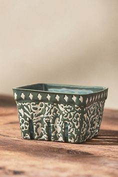 a green and white planter sitting on top of a wooden table