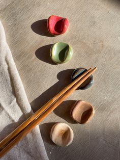 three different colored rocks and two wooden chopsticks on a table next to each other