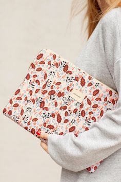 a woman is holding an orange and red floral print case