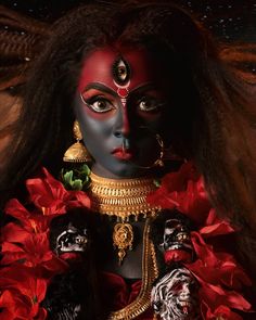 a woman with black face paint and red flowers in her hair, wearing an elaborate costume