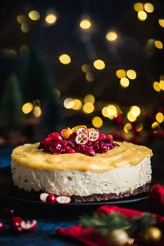 a cheesecake topped with cranberries and pomegranates on a black plate