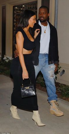 a man and woman walking down the street with one holding a handbag in her other hand