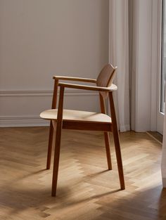 a wooden chair sitting on top of a hard wood floor next to a white wall