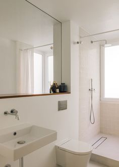 a white toilet sitting next to a bathroom sink under a large mirror on the wall