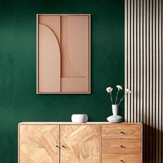 a vase with flowers sitting on top of a wooden dresser next to a green wall