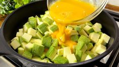 a pan filled with sliced up vegetables and sauce being poured into the skillet to cook them