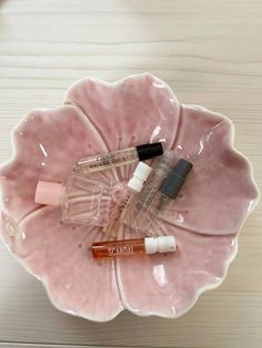 a pink flower shaped bowl with three small bottles in it