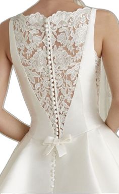 the back of a woman's white wedding dress with lace detailing and buttons on it