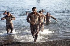 men in mud suits are running into the water