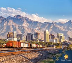 a train traveling through a city with mountains in the background