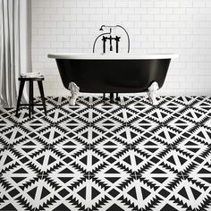 a black and white bathroom with a claw foot bathtub on the floor, two stools next to it