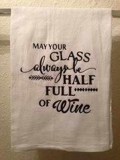 a tea towel hanging on a clothes line that says, may your glass always be half full of wine