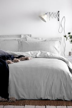 an unmade bed with black and white striped comforter on top of it in a bedroom