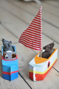 two small toy boats with animals in them on a wooden floor next to each other