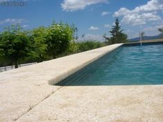 an empty swimming pool surrounded by trees and blue skies with clouds in the sky above