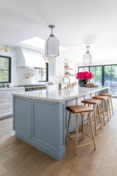 a kitchen island with stools in front of it and windows to the other side