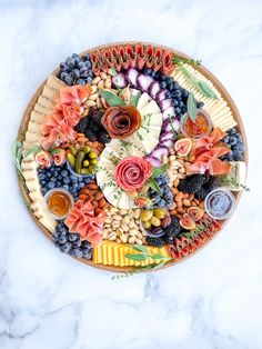 a platter filled with different types of cheeses and fruits on top of a marble table