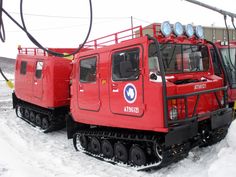 two red snow plow trucks parked in the snow