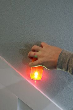 a person holding a lit candle in their left hand on the edge of a wall