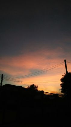 the sun is setting behind some power lines