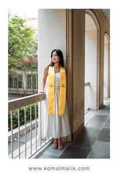 a woman wearing a yellow and white scarf leaning against a wall with her hand on the railing