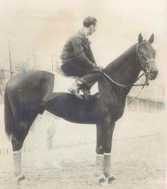 an old black and white photo of a man sitting on top of a brown horse