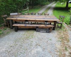 a wooden table and benches sitting on top of a gravel road