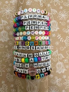 a stack of bracelets with words written in different languages on them, hanging from a wall