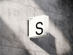 a white sign mounted to the side of a cement wall next to a shadow filled wall