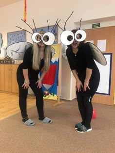 two women dressed in costumes with large eyes and antennae, standing next to each other