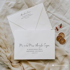 an envelope and two wedding rings on top of a bed