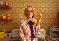 a woman sitting on top of a stove while talking on a phone with a purple tie