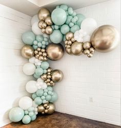 balloons are arranged in the shape of a letter on a wooden table next to a white brick wall