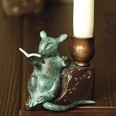 a small green mouse figurine next to a lit candle on a wooden table