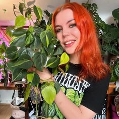 a woman with red hair is holding a potted plant