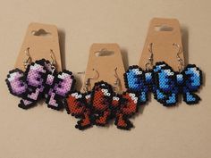 four pixelated video game characters are hanging from earrings