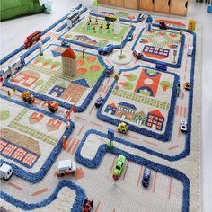 a child's play area with cars and trucks on the rug, including toys