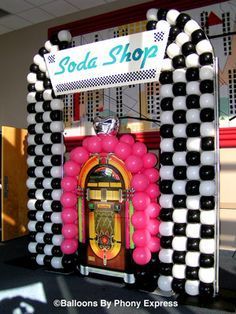 an old fashion jukebox with balloons on display in front of a soda shop sign