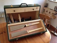 an open suitcase sitting on top of a wooden table next to a knife and some knives