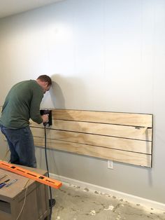 a man using a power drill to install wood planks in a room with white walls