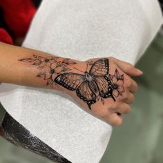 a woman's arm with a butterfly and flowers tattoo on the left side of her hand