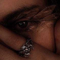 a close up of a person's face with a ring on their finger and her eyes